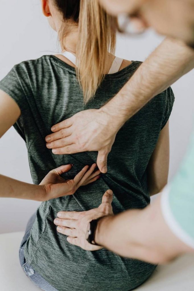 Osteopath with arms reaching out to treat a woman’s upper back pain using osteopathy techniques